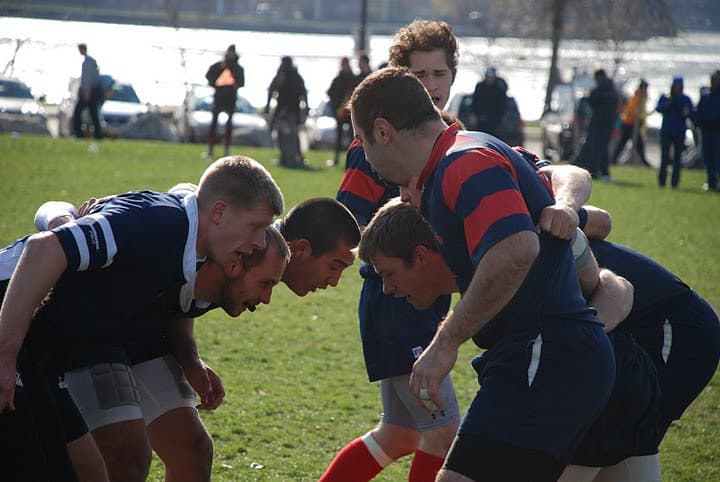 Sacred Heart Rugby forwards bound shoulder to shoulder in a scrum, heads down, waiting for the ball to be fed in.