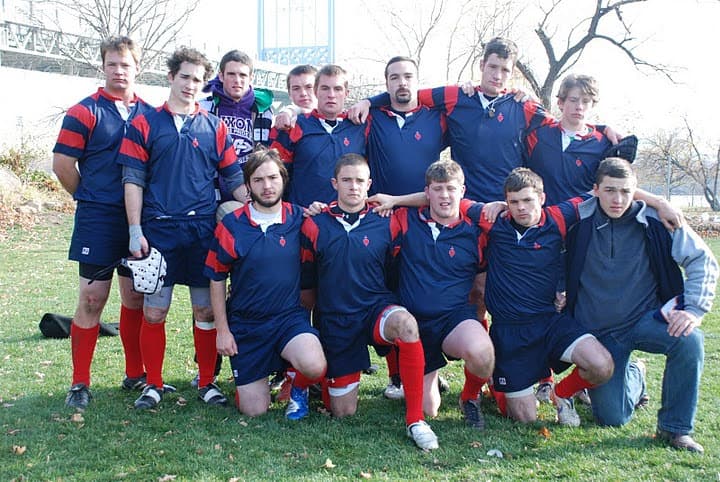 The Sacred Heart Rugby men's squad lined up together on the pitch in navy and red jerseys with the club crest on the chest.